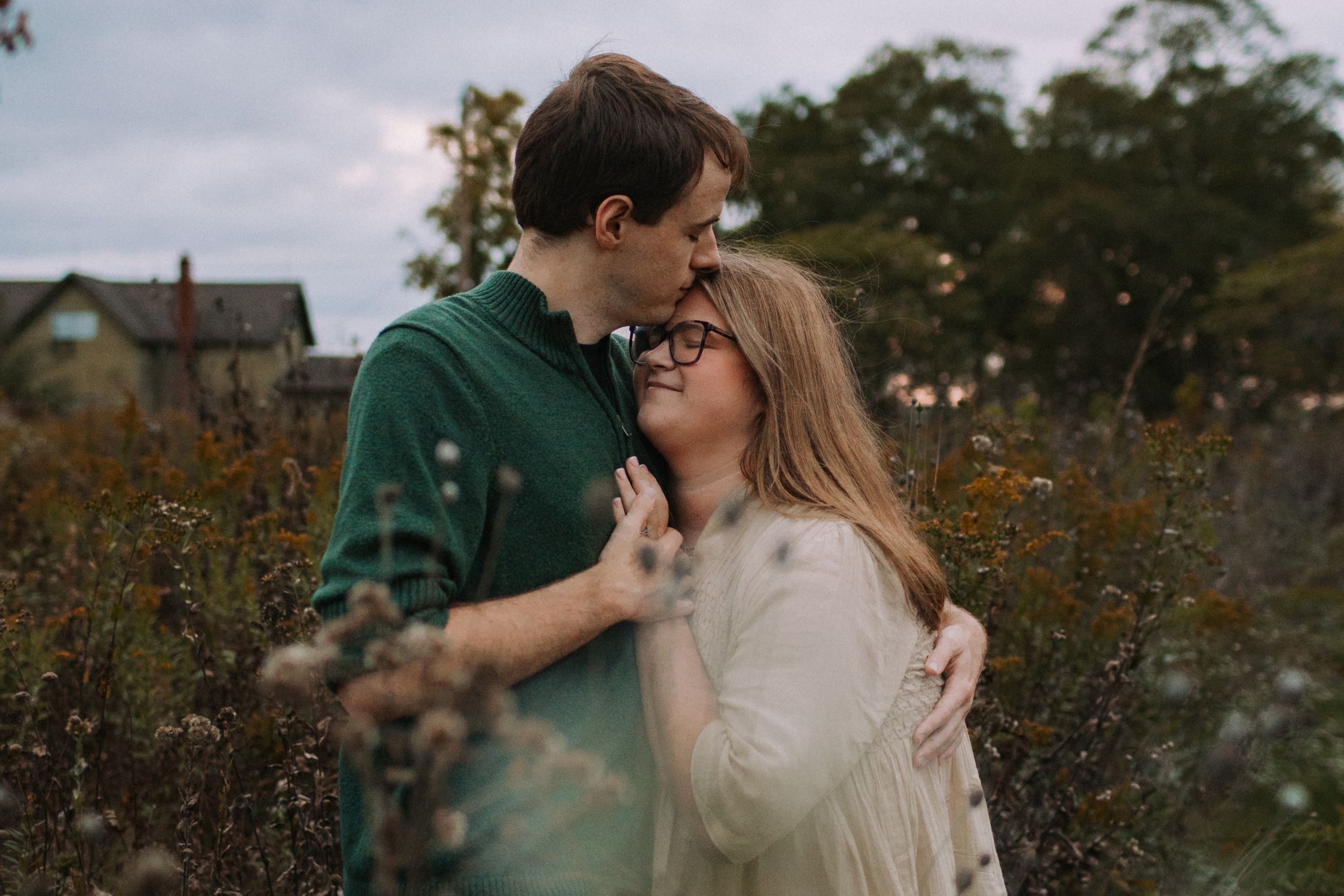 A tender embrace captured in an outdoor garden setting during golden hour.