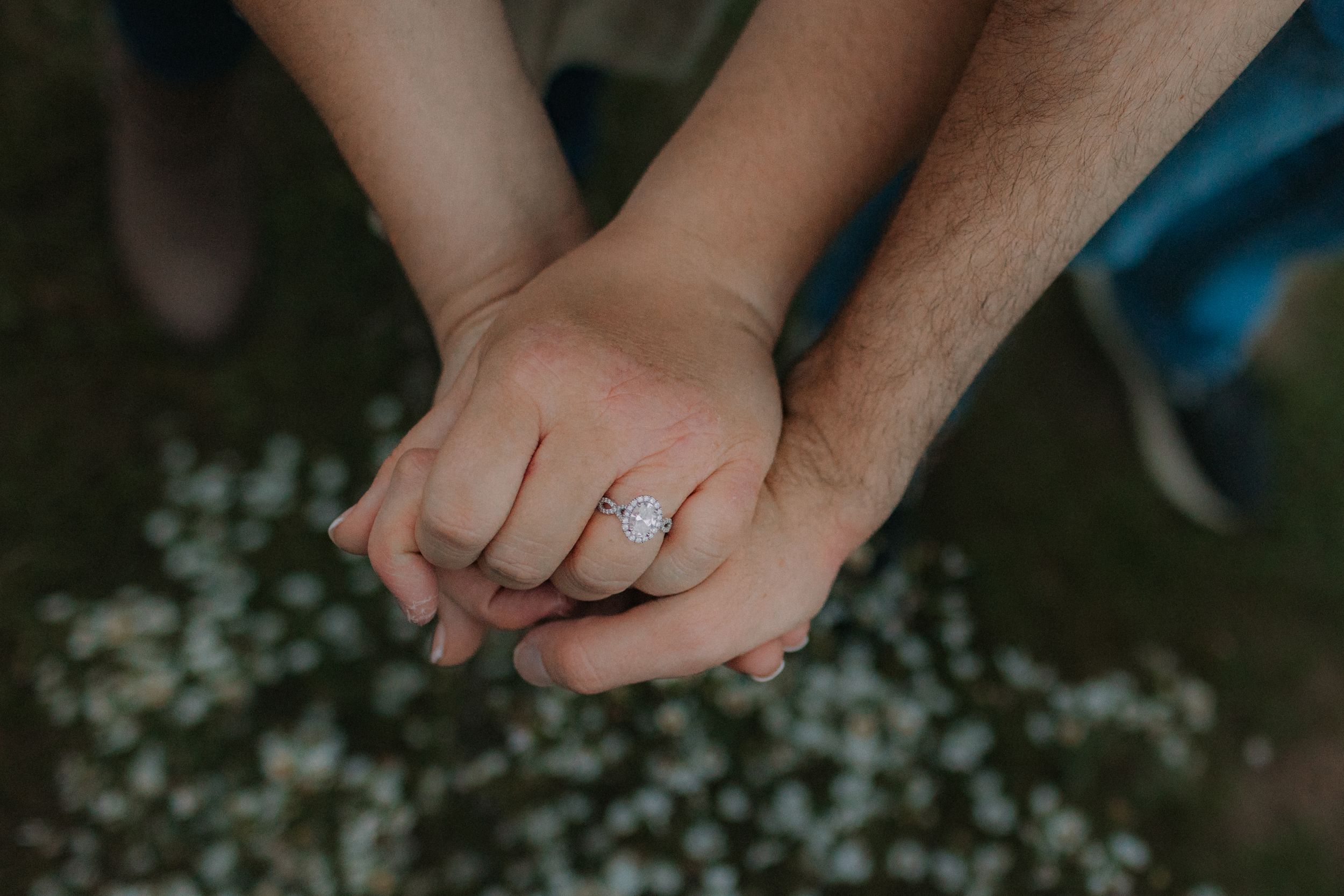 Close-up of hands gently touching against a blurred natural background.