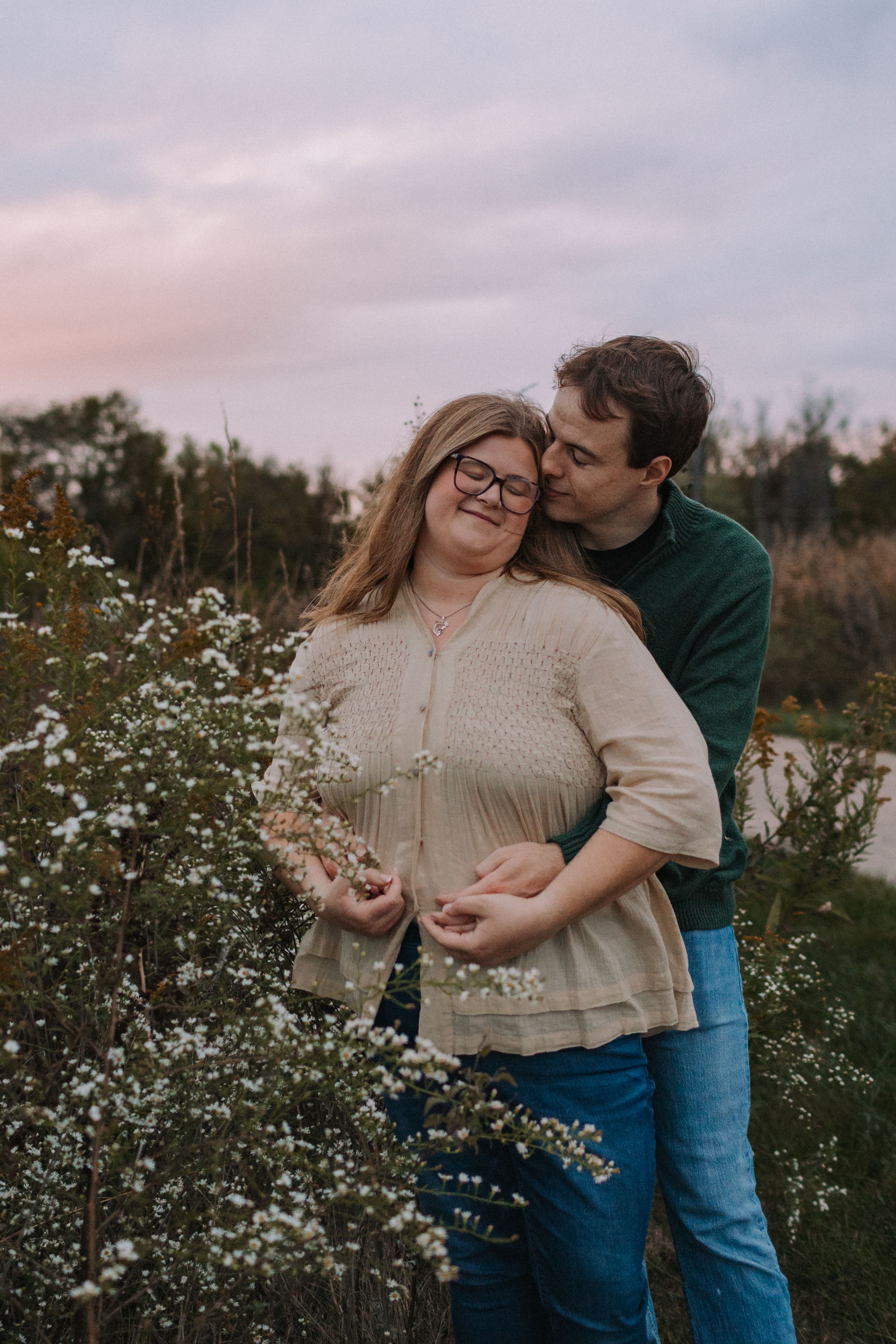 A couple shares tender moments among blooming white wildflowers at sunset.
