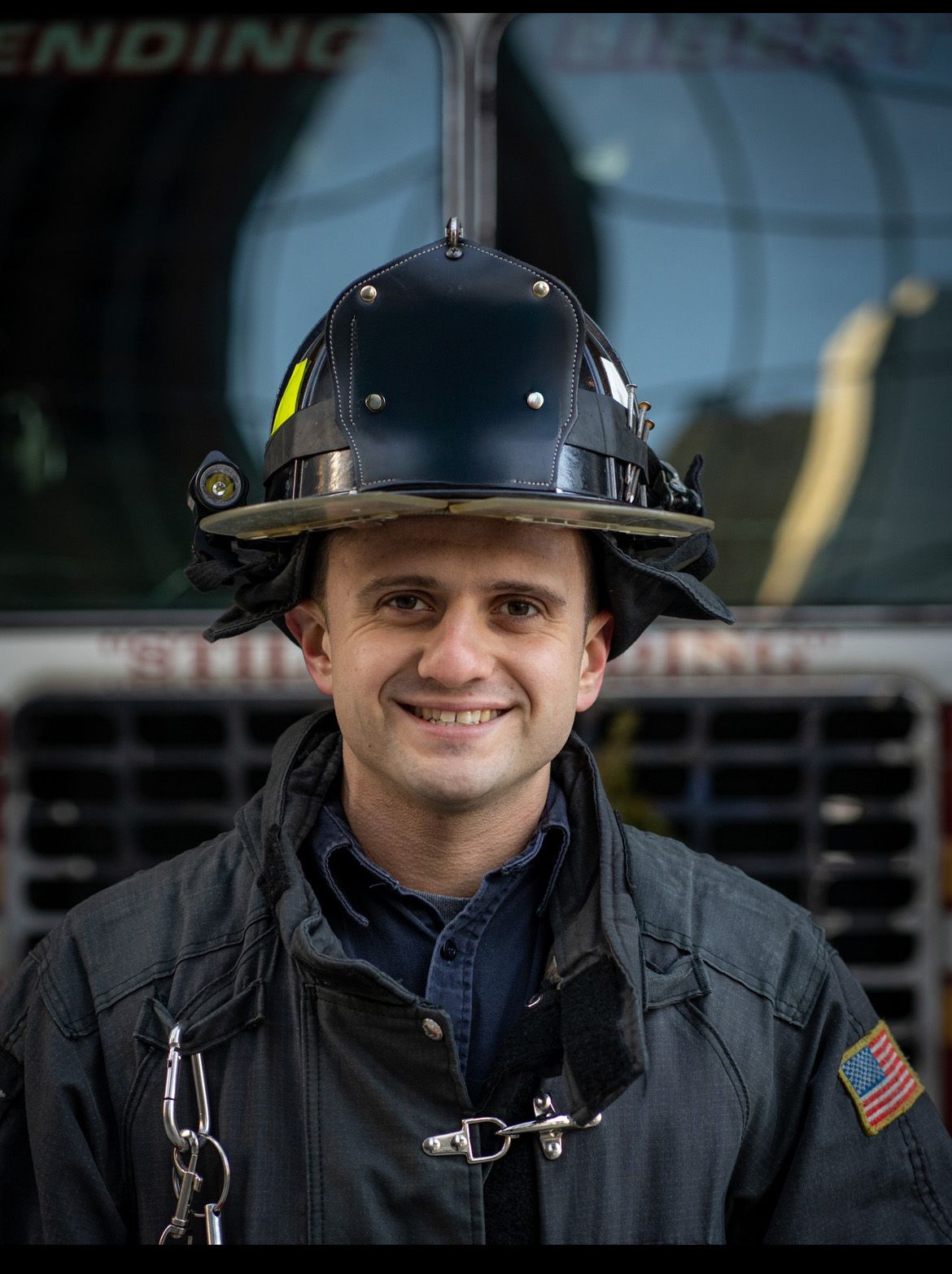 A firefighter in protective gear and helmet stands ready for duty with safety equipment visible.