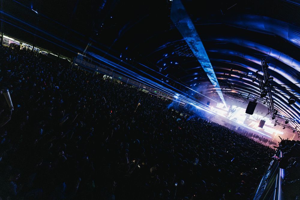 A dark stage illuminated with dramatic blue and purple lighting effects during a live performance.