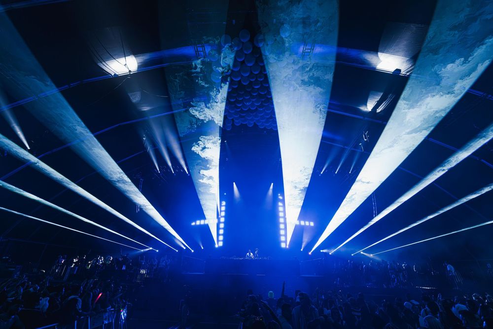 Concert stage illuminated with dramatic blue lighting and fog effects creates an atmospheric performance environment.