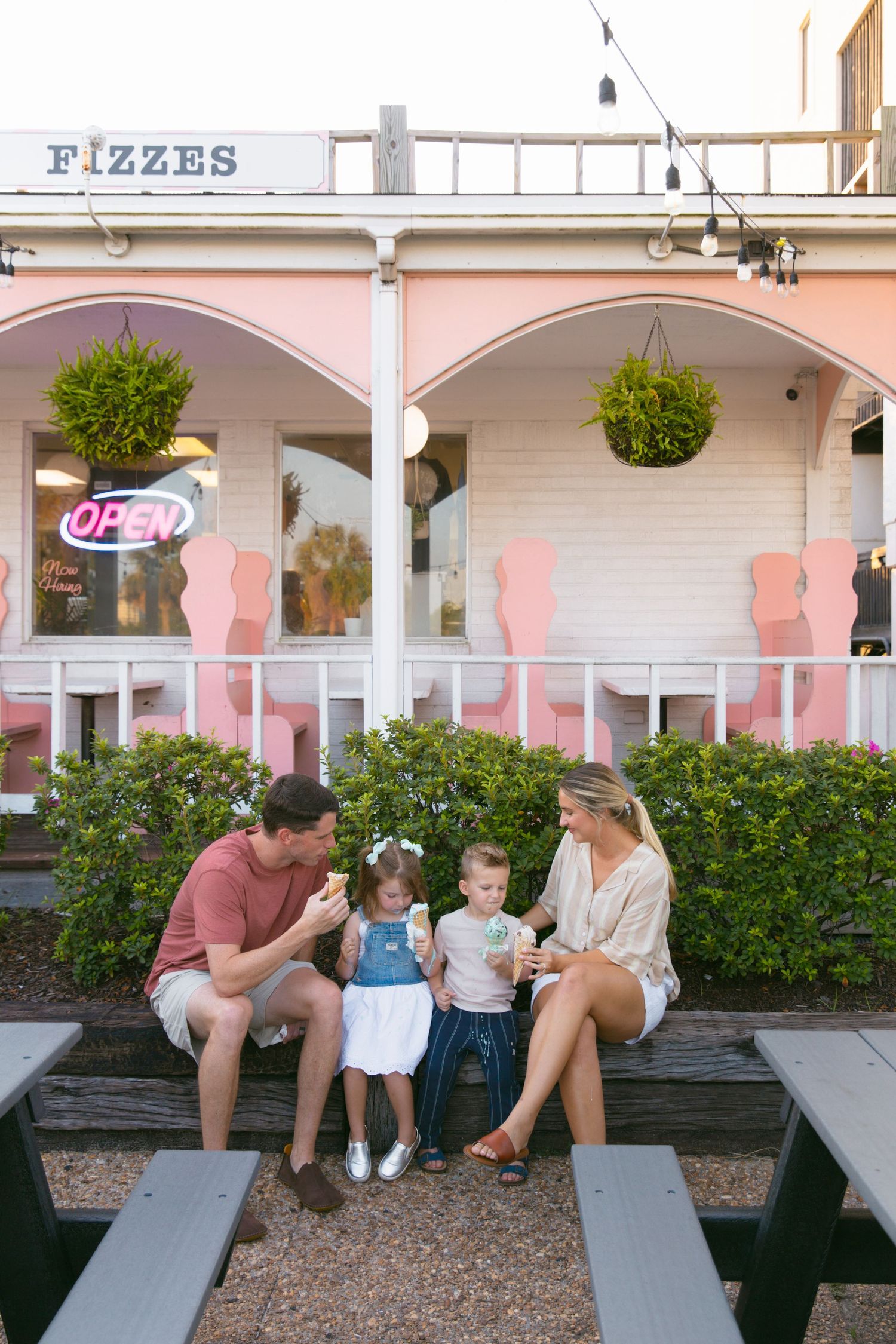 Family sharing ice cream treats at a picnic table outside pink Fizzes ice cream shop.