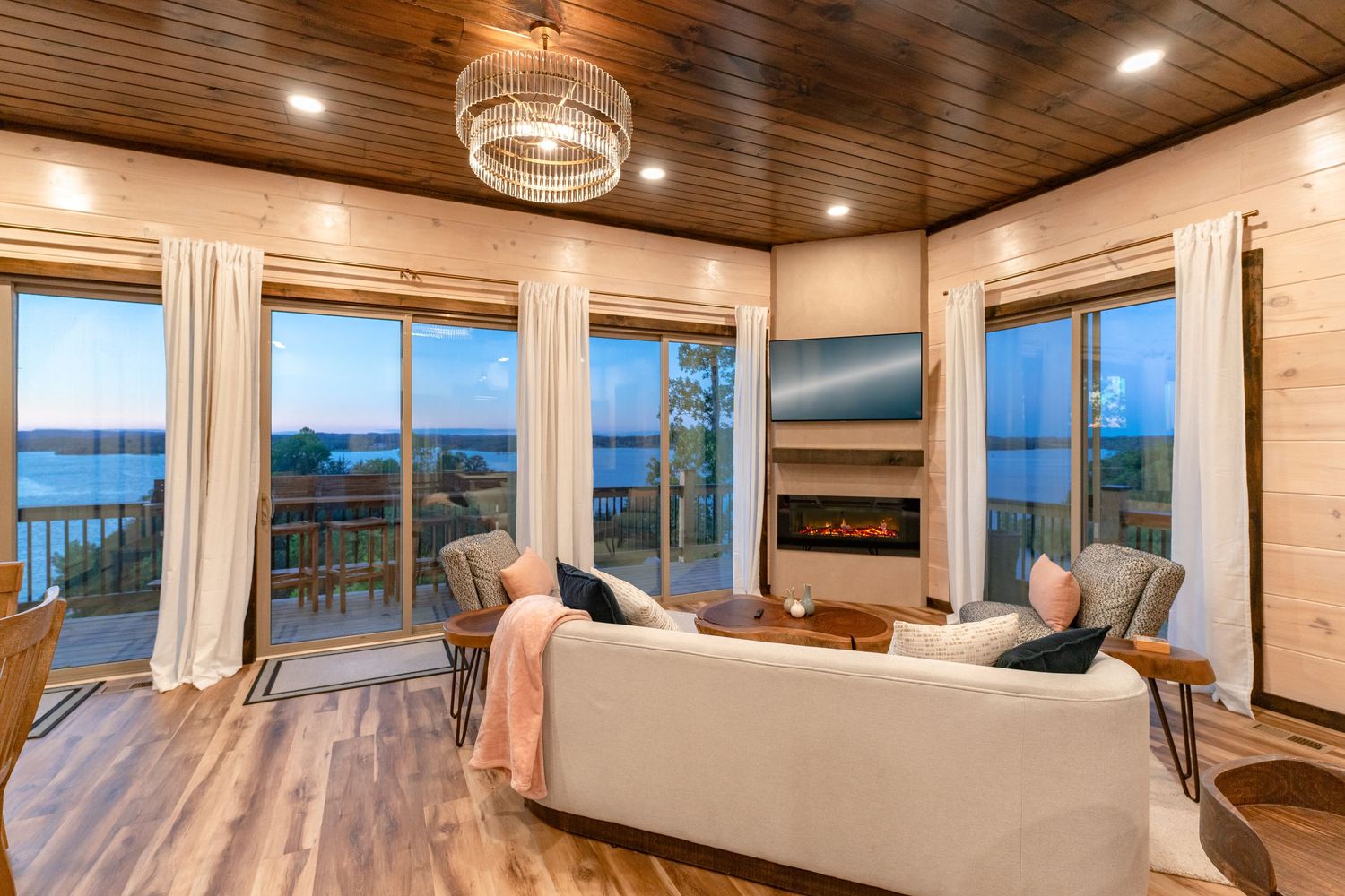 Coastal-inspired living room with wood ceiling, crystal chandelier, and panoramic ocean views.