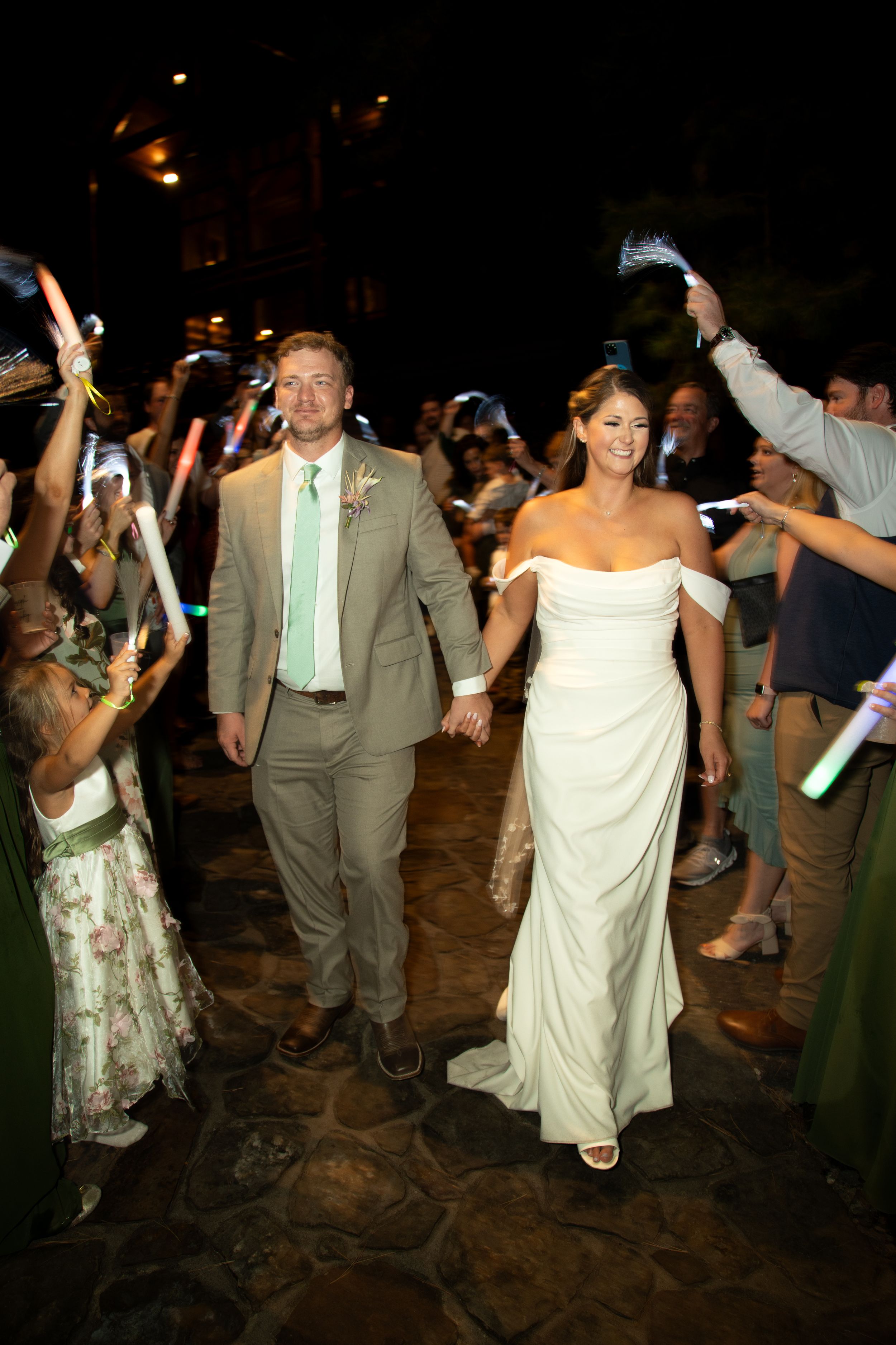 Wedding reception dance party at night with guests celebrating on a stone patio.