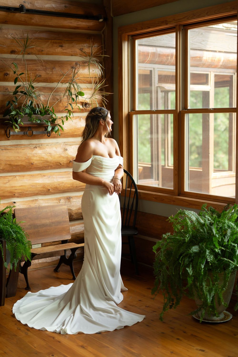 Wedding dress flows elegantly in rustic wooden cabin interior with natural lighting.