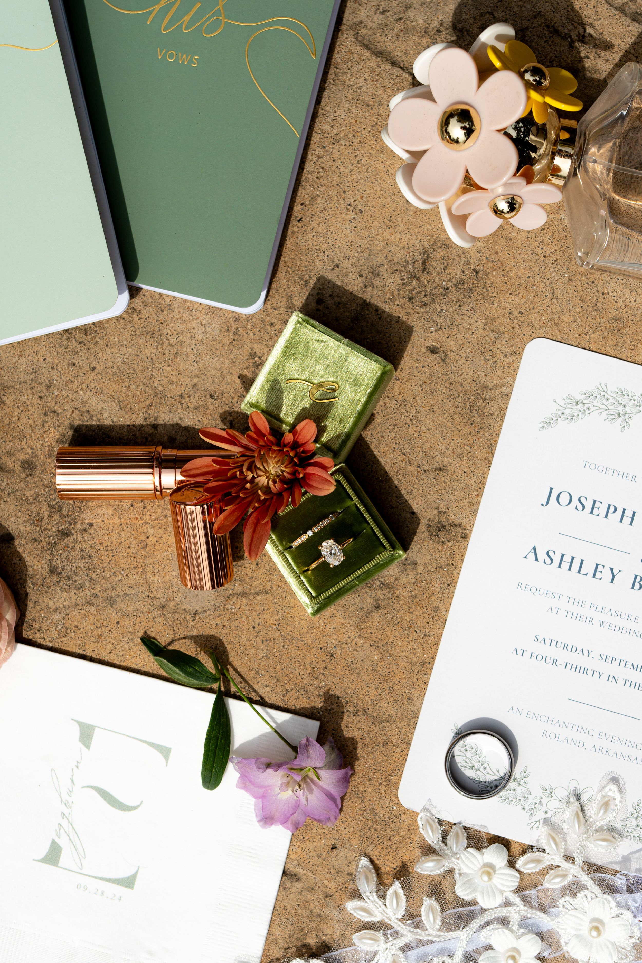 Wedding invitation suite with elegant gold calligraphy and floral details on concrete background.