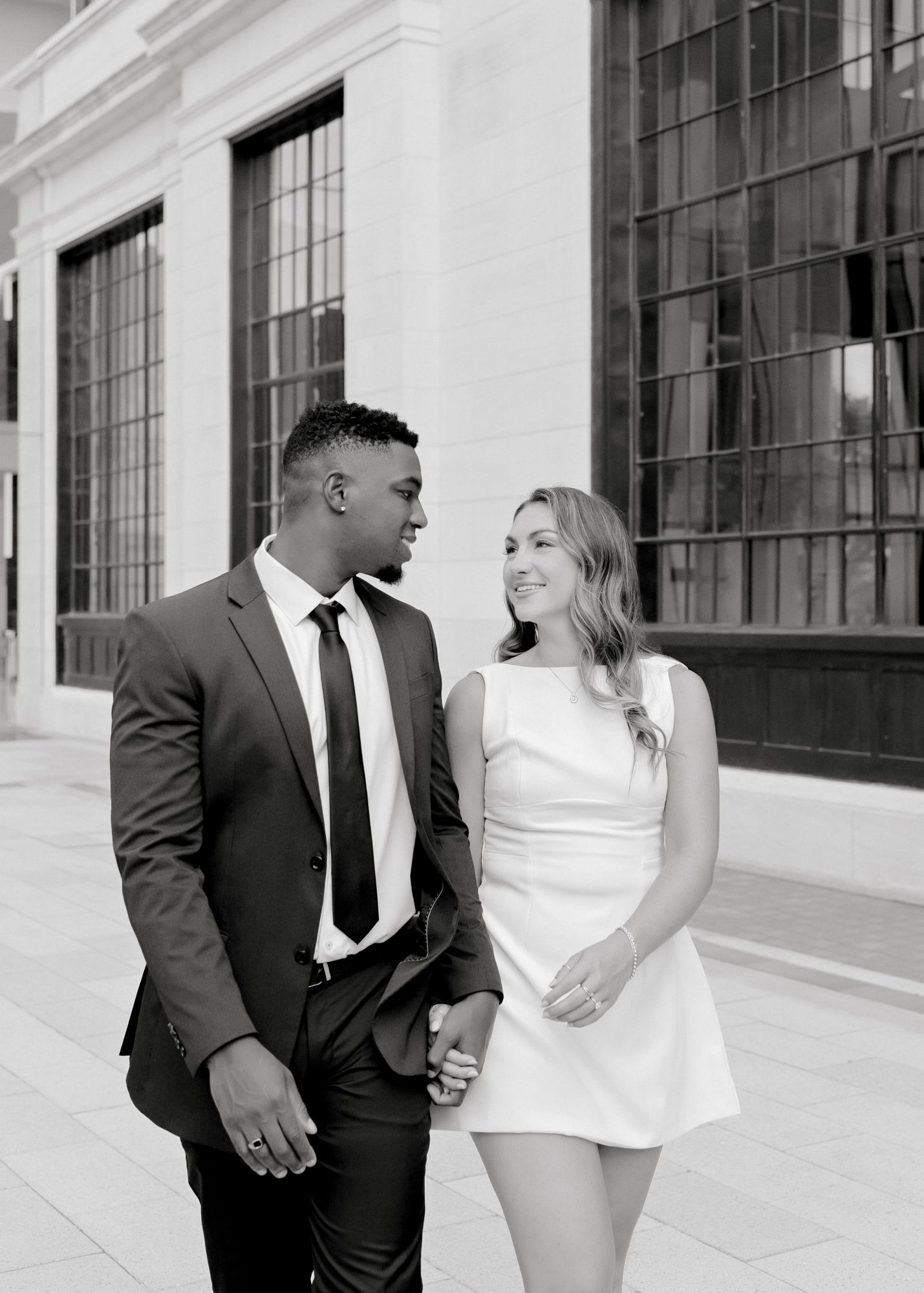 A couple in formal attire sharing a joyful moment while walking together outdoors.