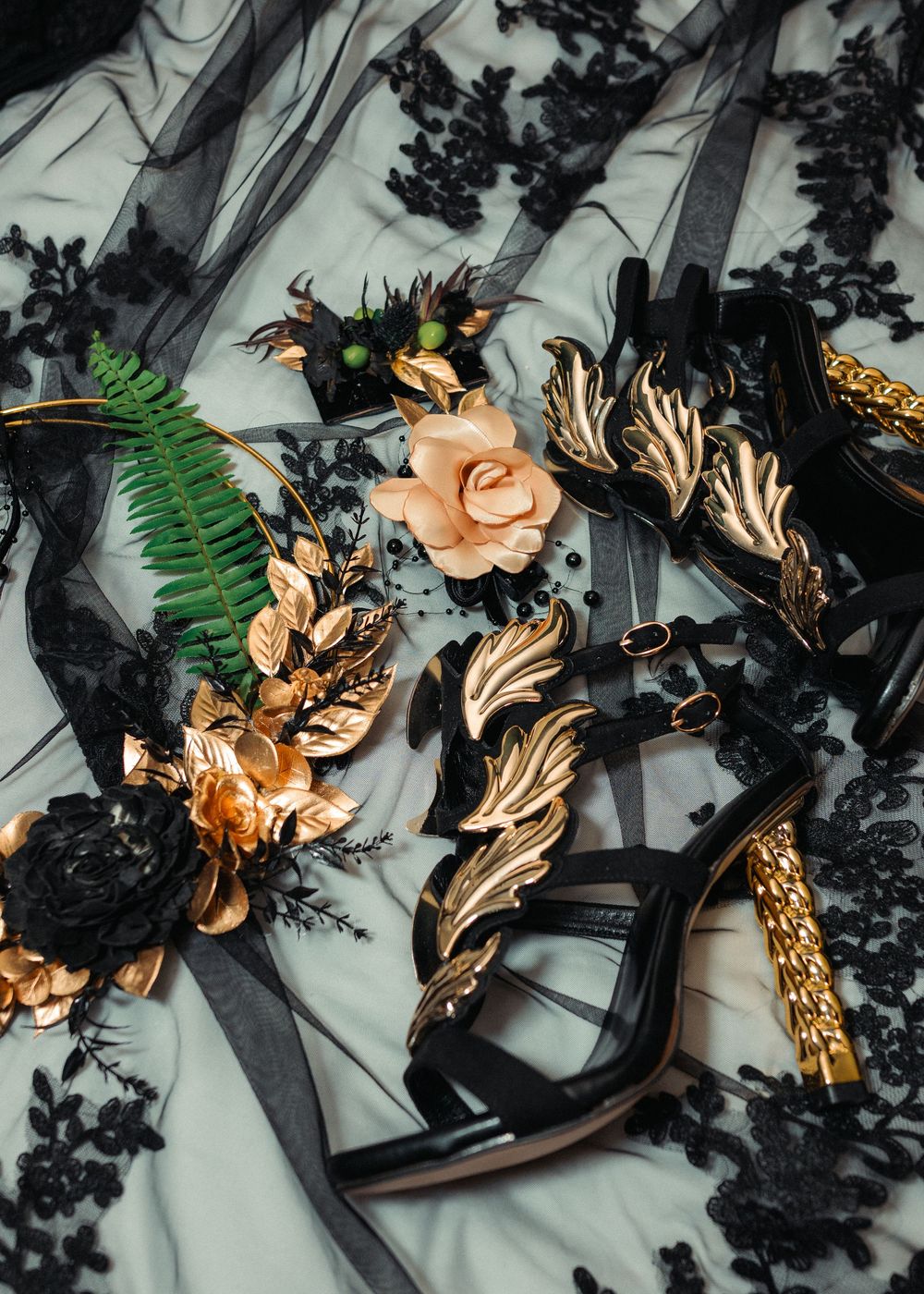 Intricate black and gold floral hair accessories with ferns and metallic details arranged on a light background.