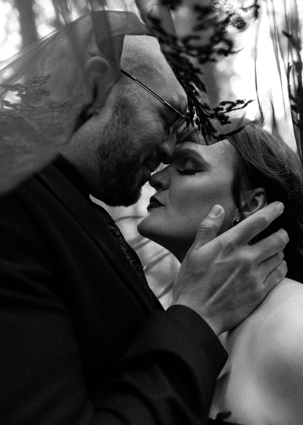 A romantic black and white portrait of a tender intimate moment between a couple about to kiss.