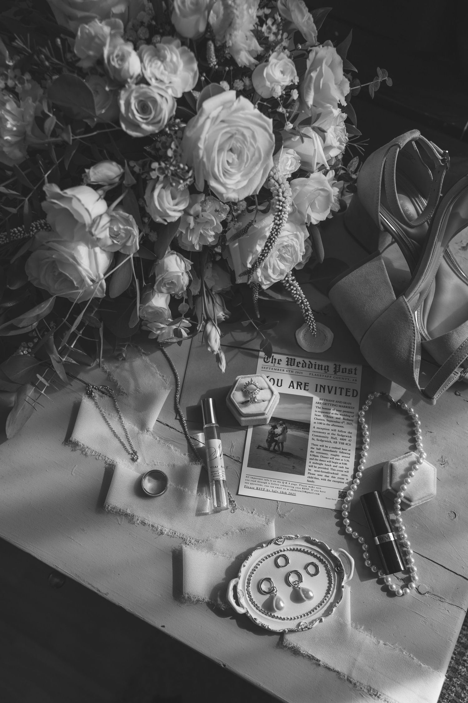 Black and white photo of elegant wedding table decor with roses and vintage accessories.