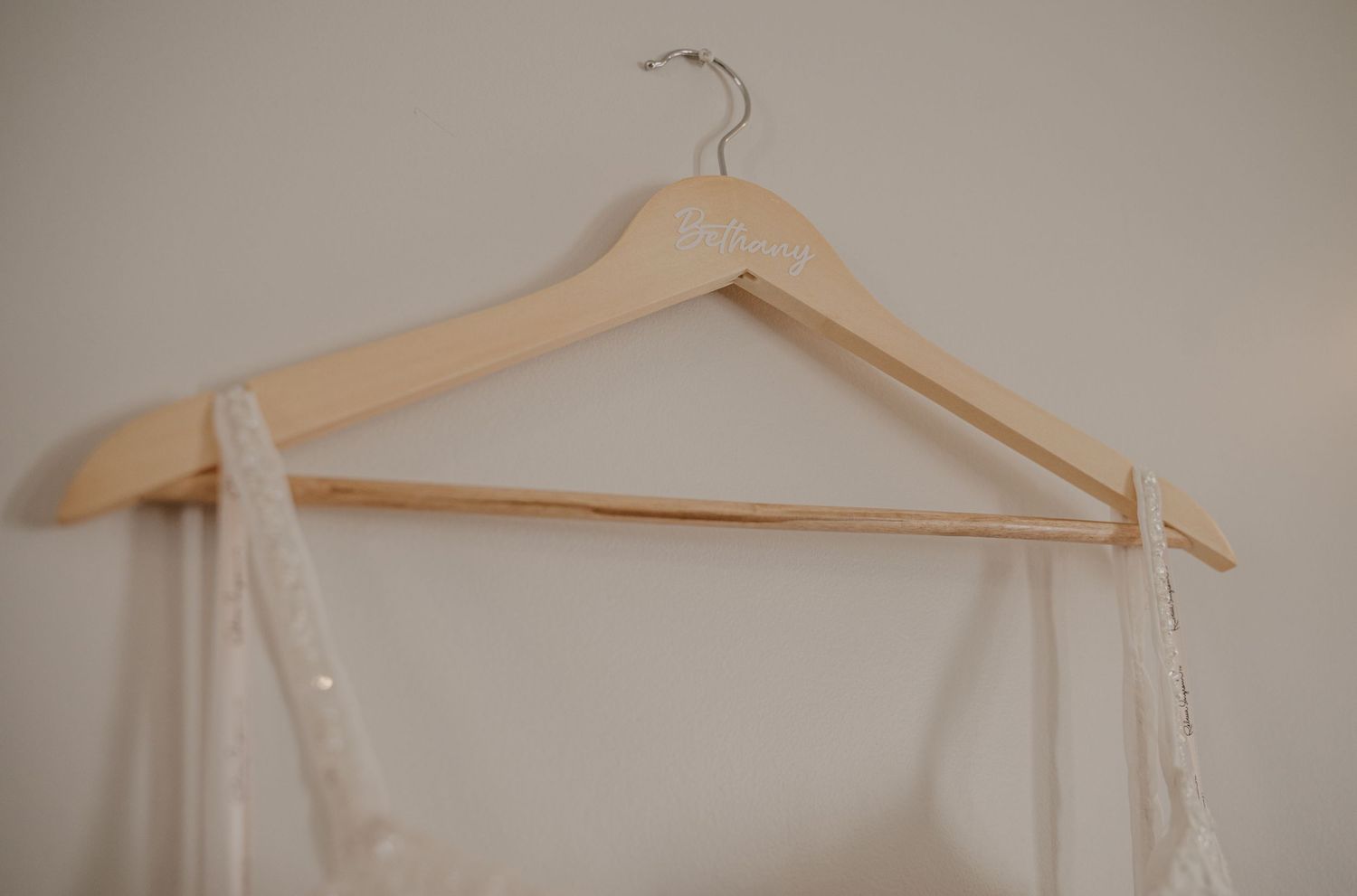 Row of wooden hangers lined up against a neutral beige wall.