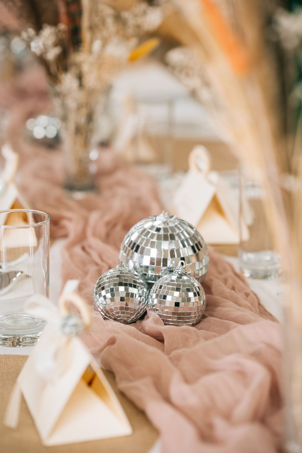 Decorative mirror disco balls and pink fabric create an elegant table setting at a wedding reception.