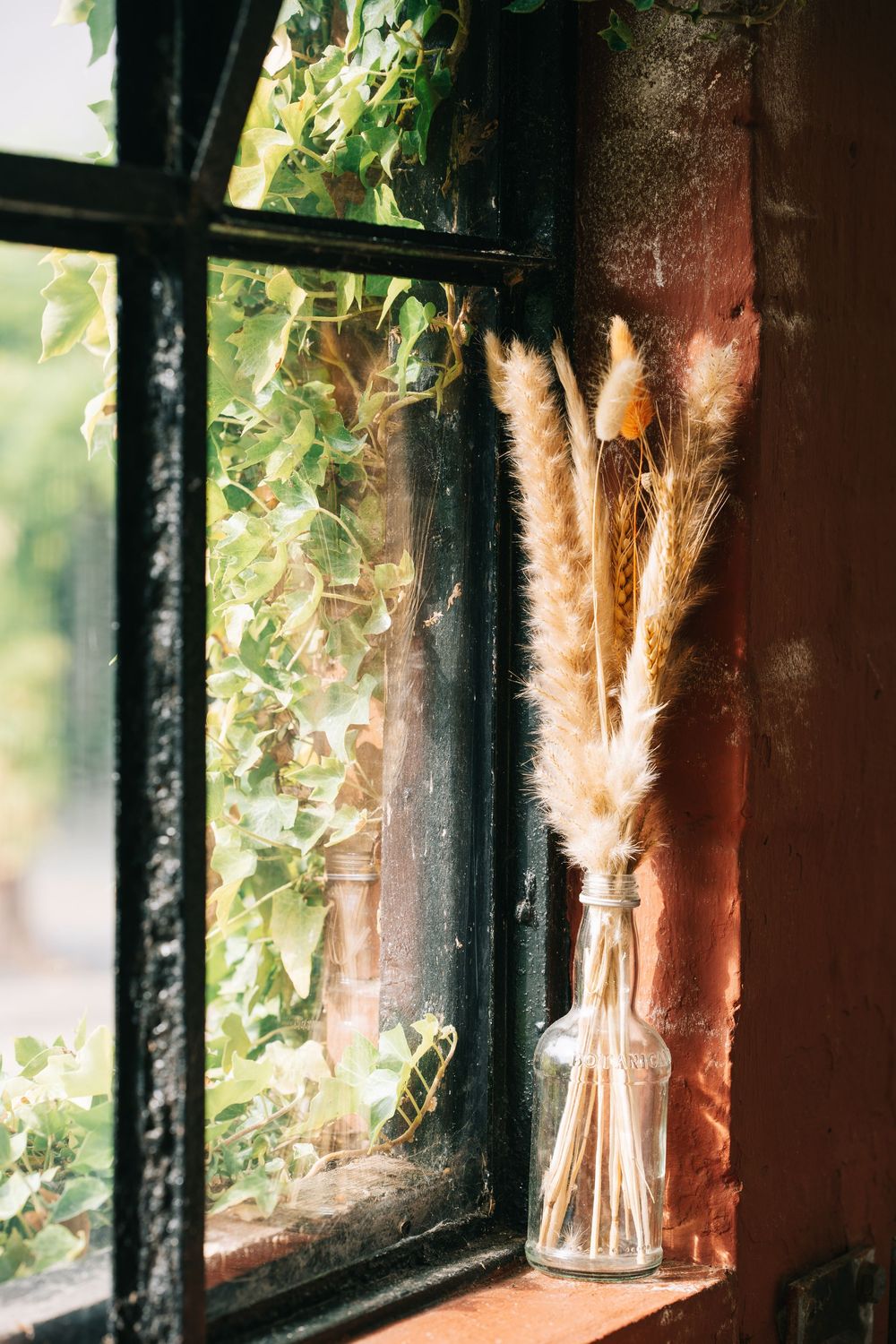 Dried flowers and greenery decorate a rustic window sill with natural sunlight streaming through.