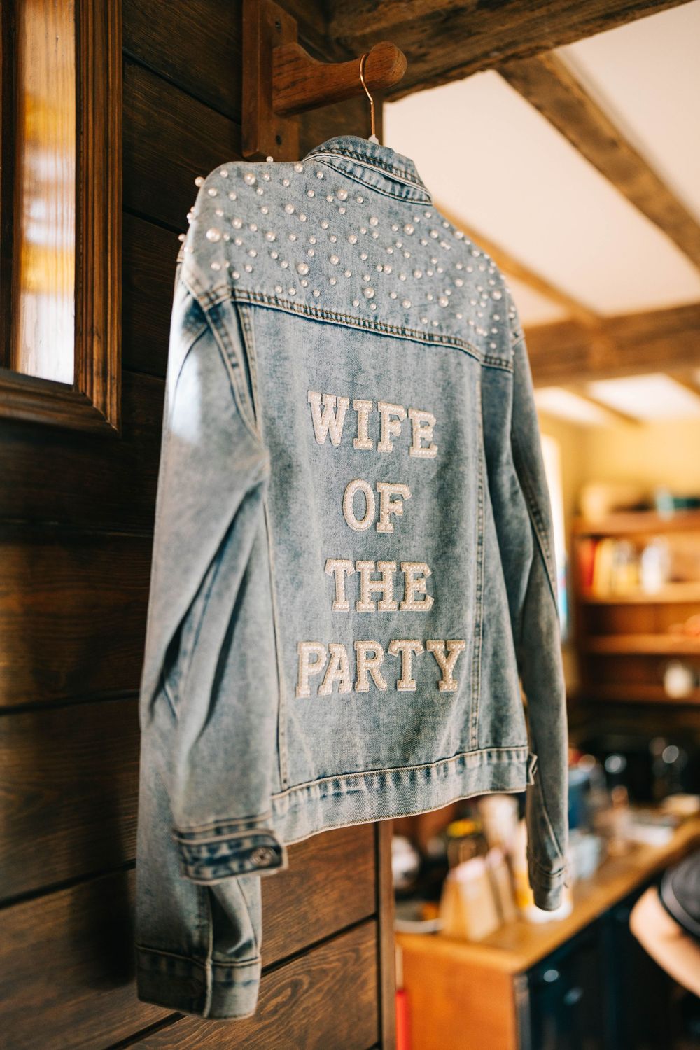 Custom denim jacket with pearl embellishments displays 'WIFE OF THE PARTY' text across the back.