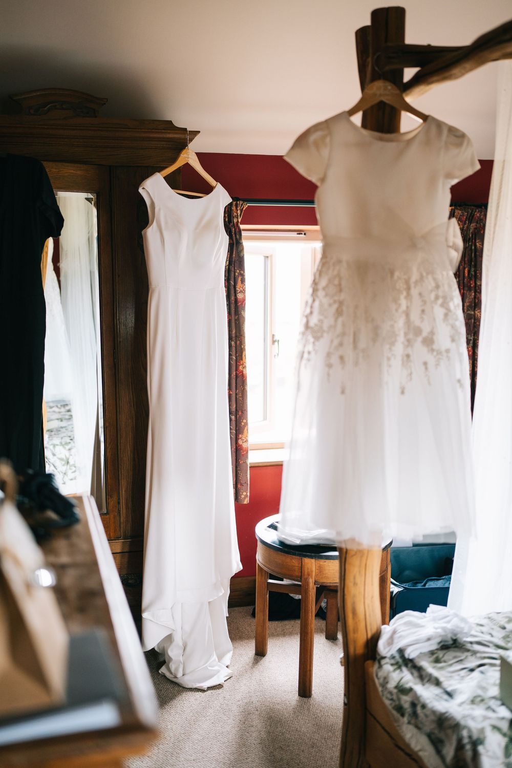 White wedding dresses hanging in a rustic room with natural light streaming through windows.