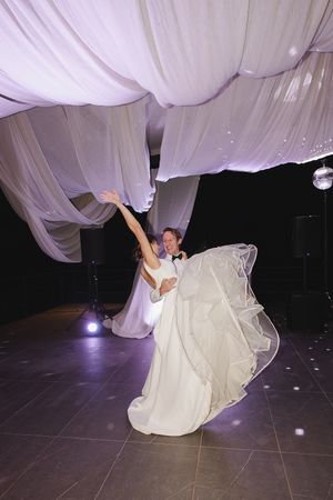 Happy moment between bride and groom on dancefloor during first dance.