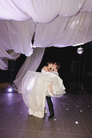 Happy moment between bride and groom on dancefloor during first dance.
