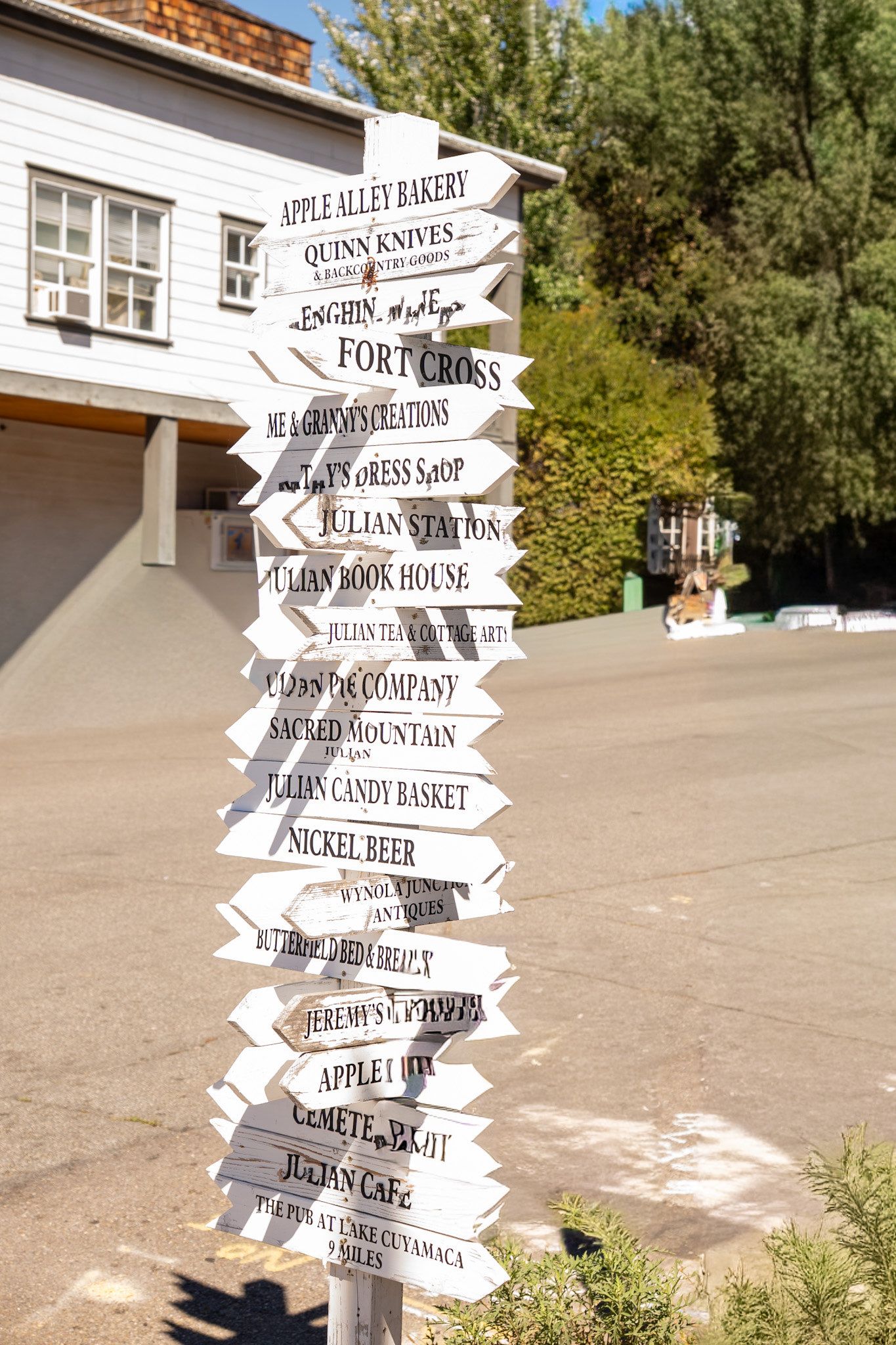 White directional sign post with multiple destination arrows in rustic outdoor setting.