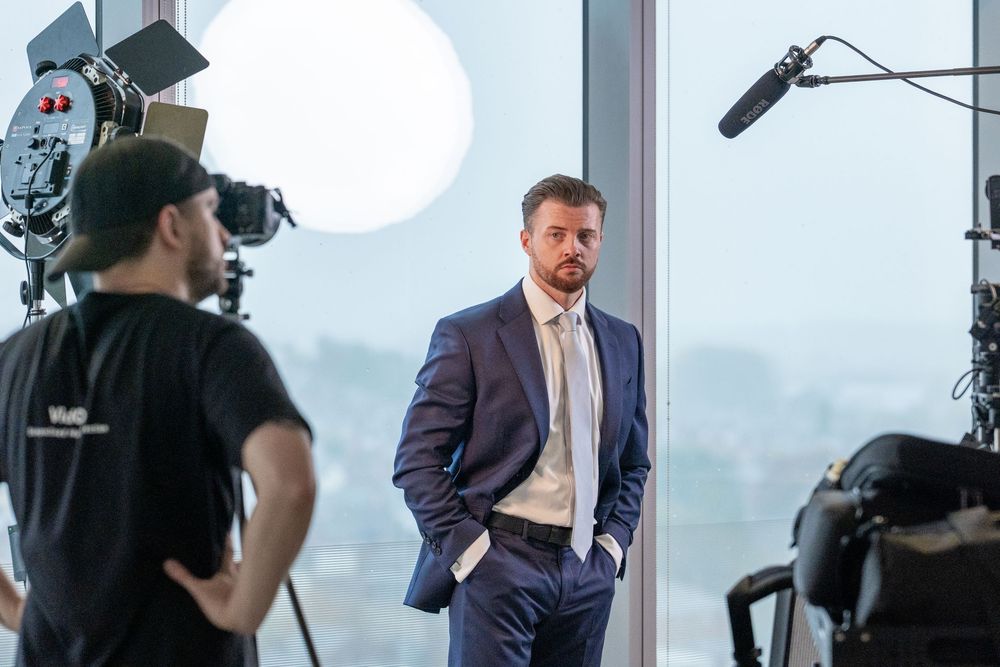 Professional film crew working on a corporate video shoot in a modern office setting with lighting and camera gear.