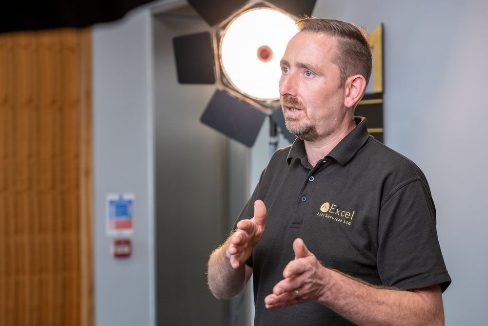Professional videographer adjusts camera settings while filming in modern office space.