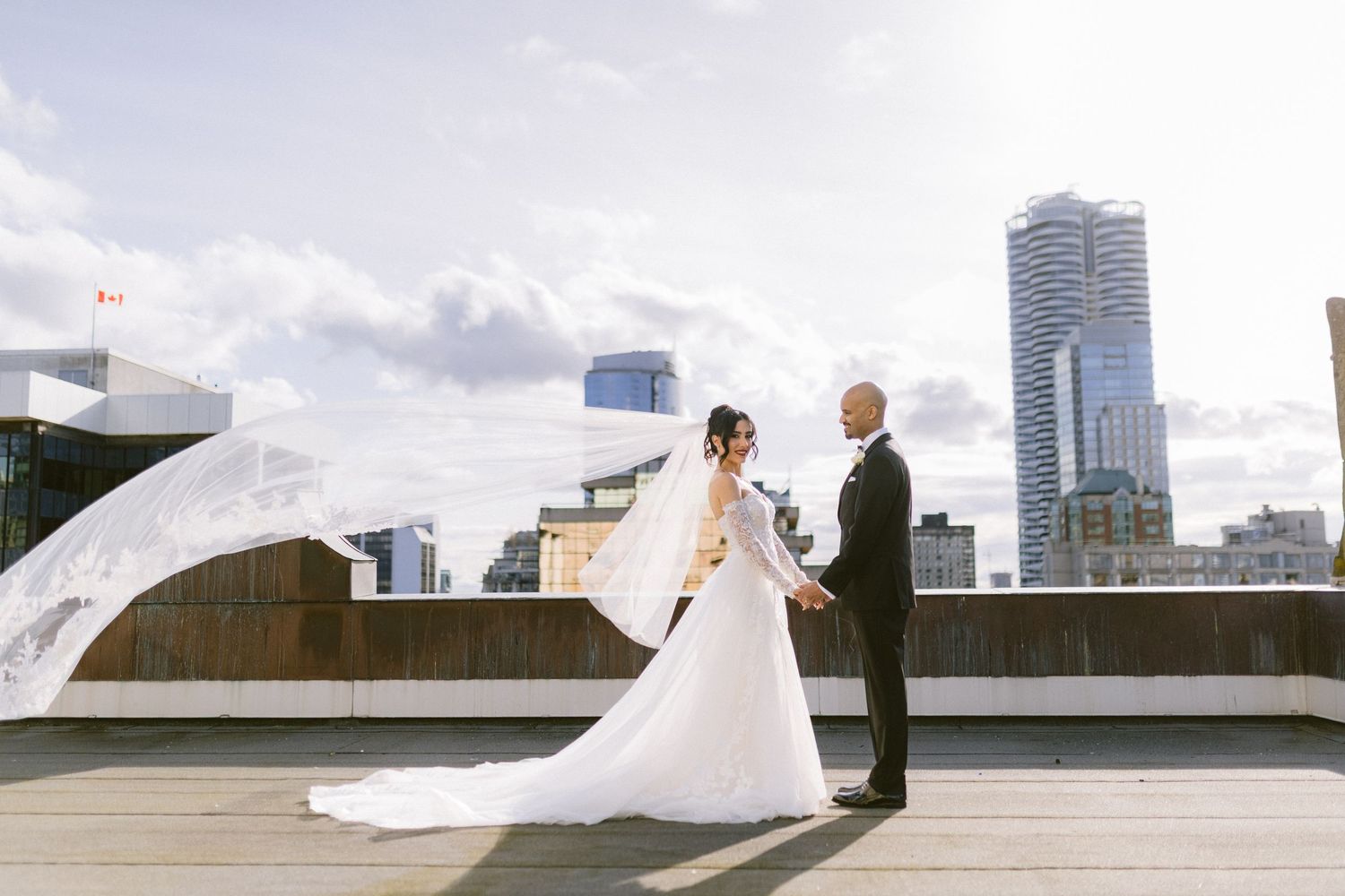 A romantic rooftop wedding moment with flowing veil against a modern city skyline.