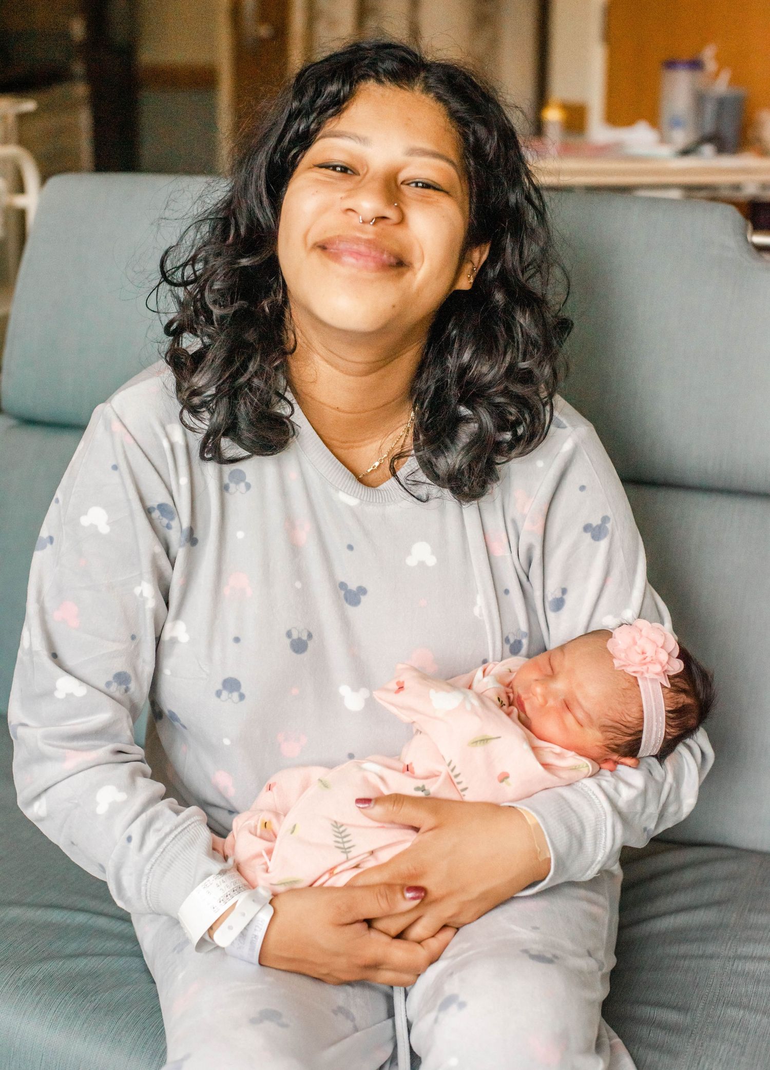 A series of four candid photos showing tender moments of a person in a floral shirt holding a newborn baby on a gray couch.