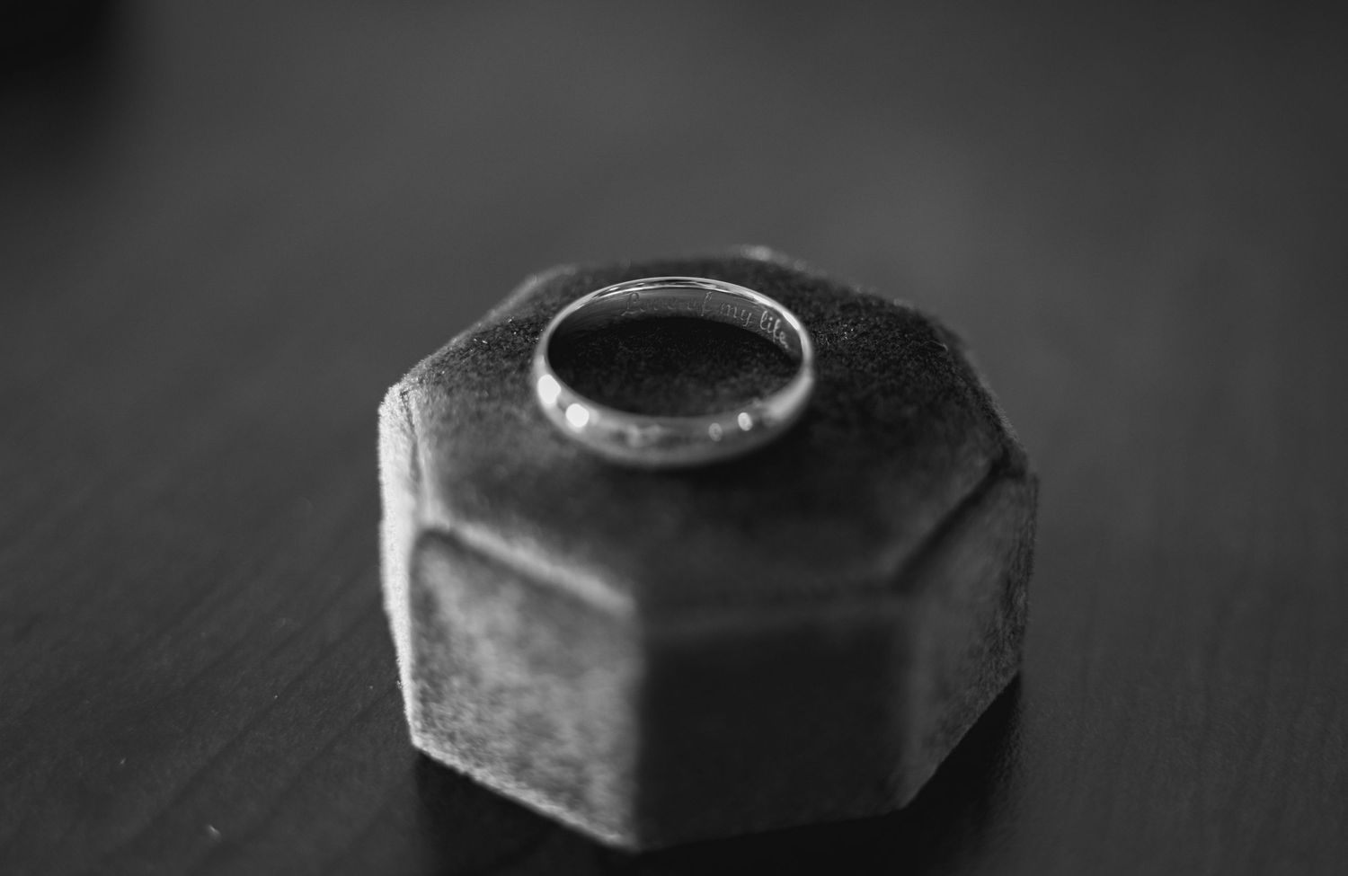Black and white macro photography of wedding rings with dramatic shadows and textures.