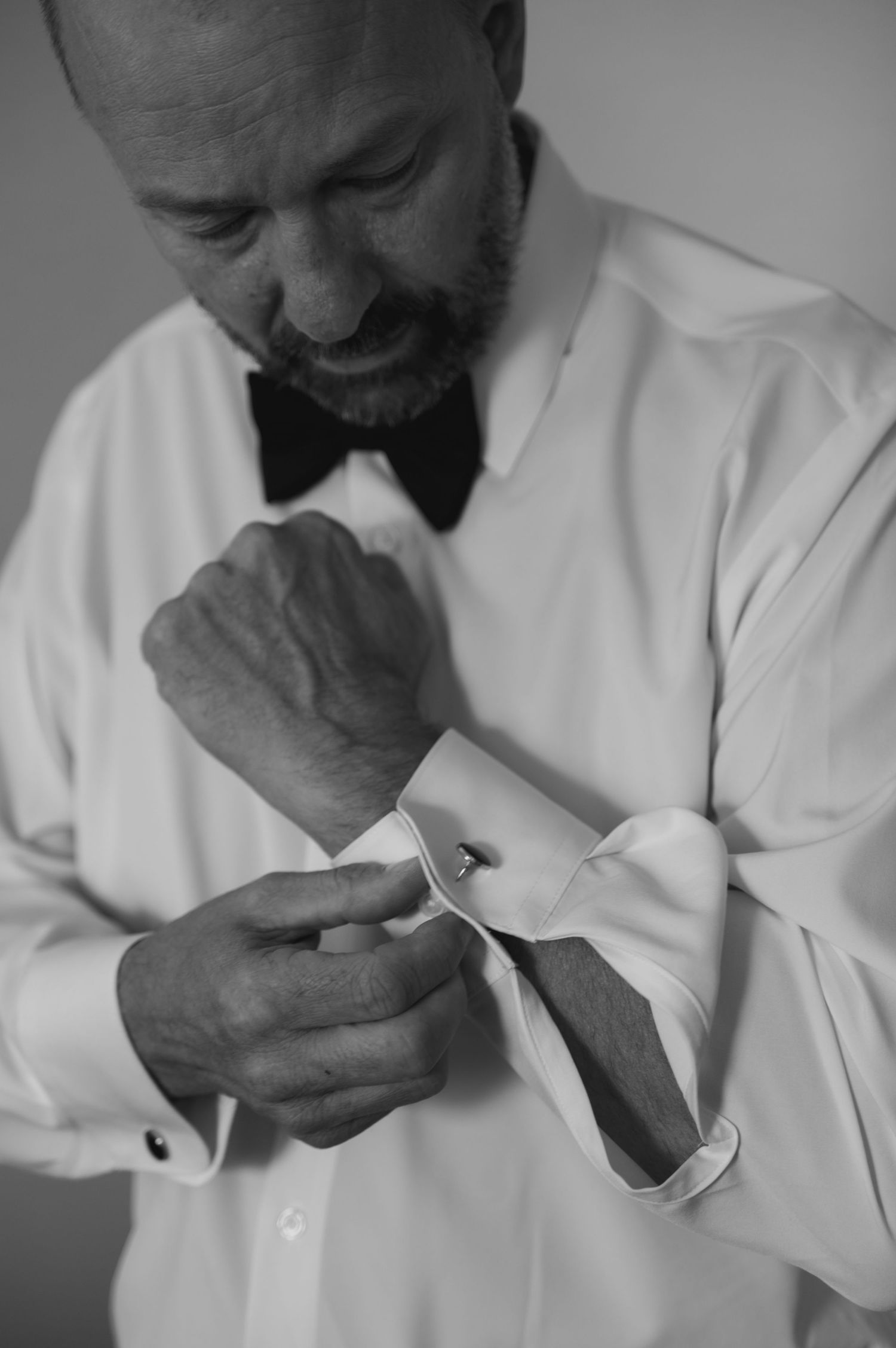 A series of black and white photos showing someone adjusting a tie and cufflinks while getting dressed.