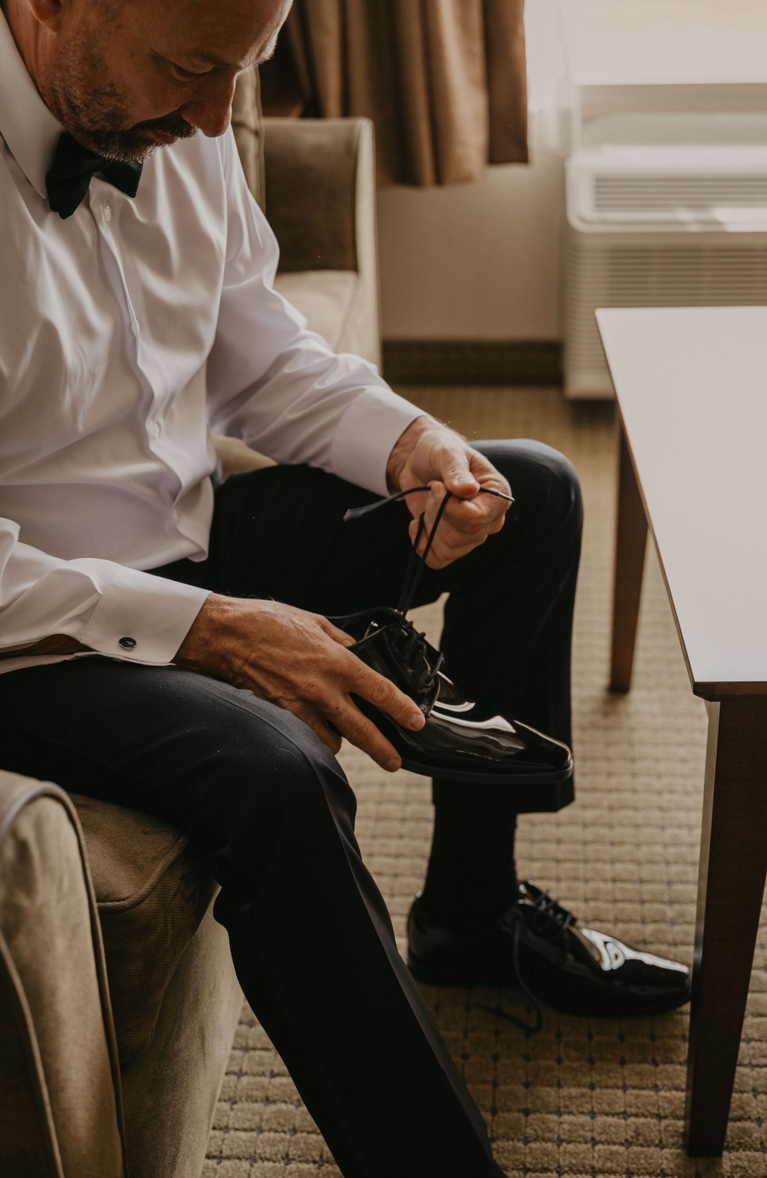Row of dress shoes and formal pants visible as people get ready for a special occasion.
