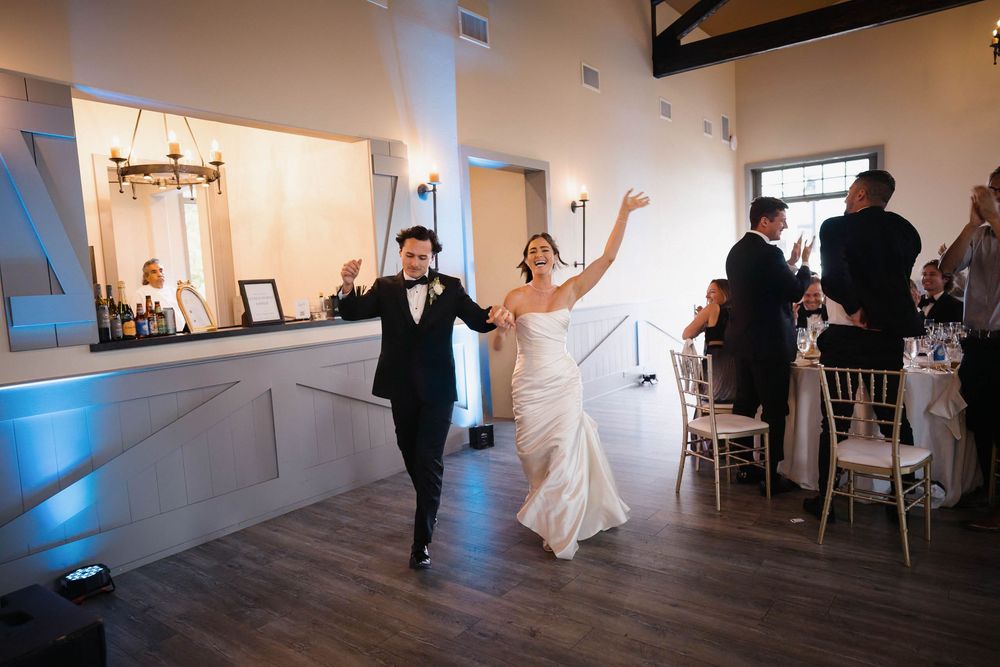 A wedding couple dances together during their first dance in an elegant white room with blue accent lighting.