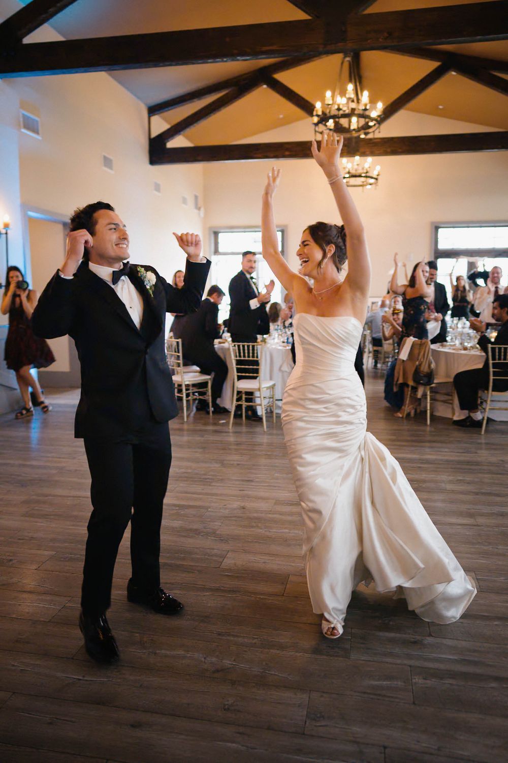 Couple dancing together at a wedding reception in an elegant venue with wooden floors and exposed beams.