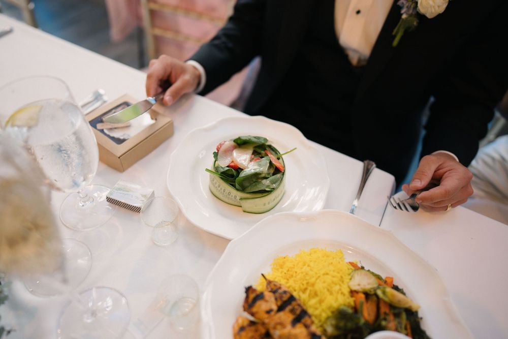 Wedding reception dining table with elegant plated meals and table settings.