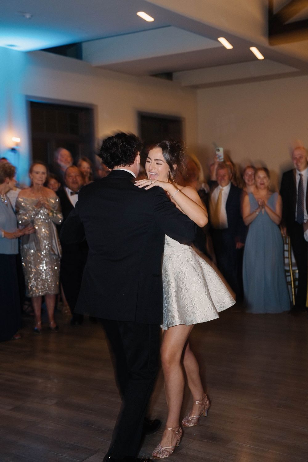Couples dancing together at a wedding reception on a wooden dance floor in an indoor venue.