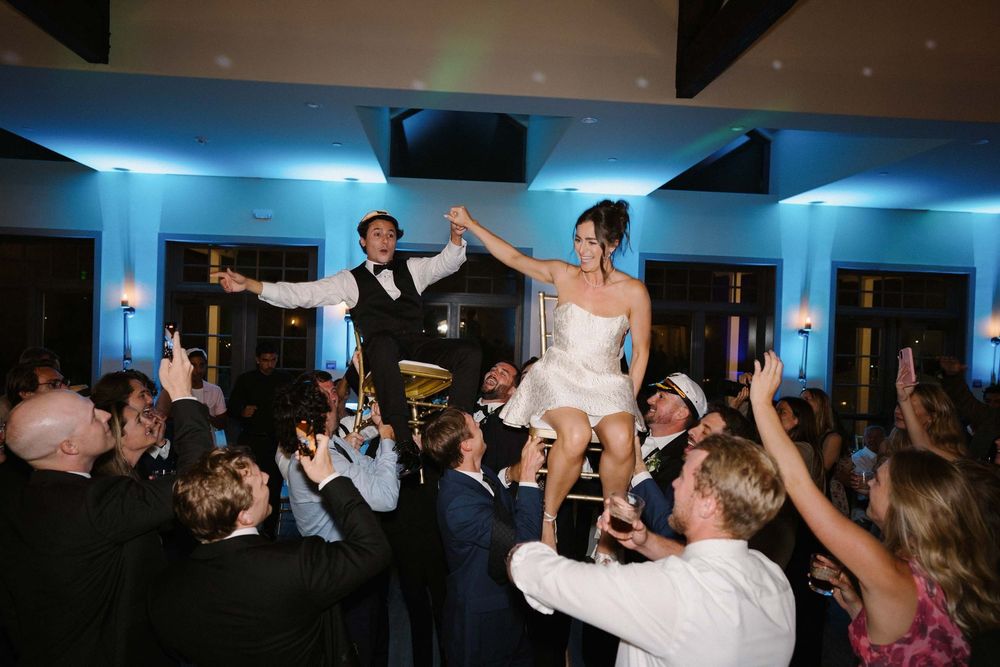 Wedding guests dance and celebrate on a dimly lit dance floor during an evening reception.