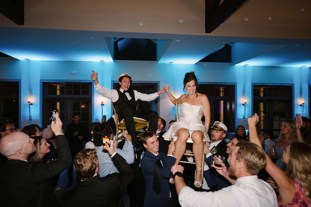 A group of people dancing and celebrating at a lively indoor party with blue lighting.
