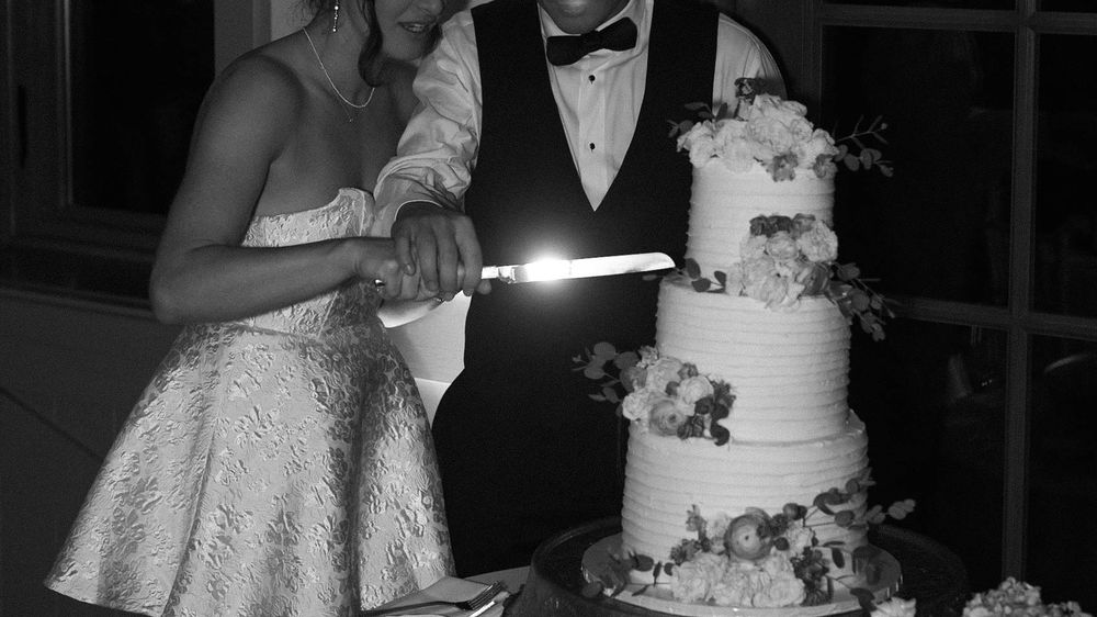A couple in formal wedding attire dance together during their reception while guests watch in the background.