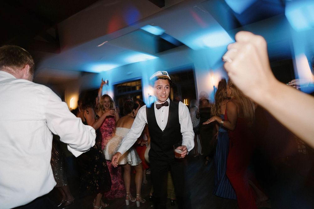 People dancing and celebrating at a lively party with blue lighting and festive atmosphere.