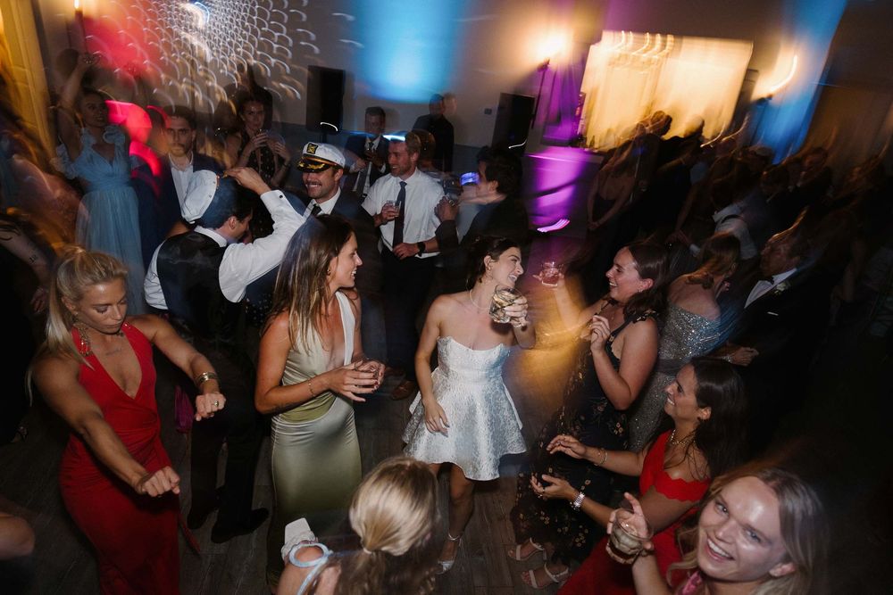 People dancing and socializing at a lively nightclub party with colorful lighting and energetic atmosphere.