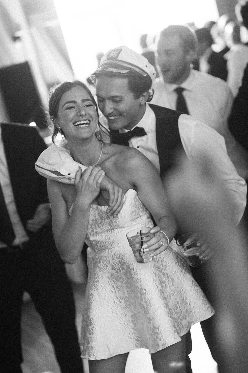 A series of black and white candid photos showing a bride and groom sharing joyful laughter during their wedding reception.