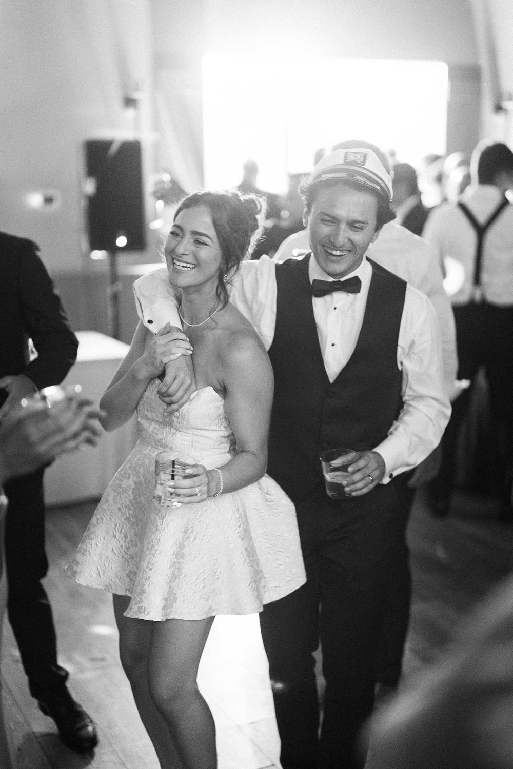 A sequence of four black and white photos showing a couple dancing and laughing together at a wedding reception.
