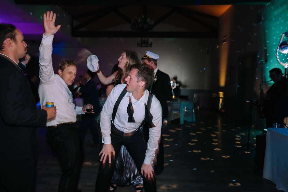 People dancing and celebrating at a wedding reception with colorful mood lighting and a festive atmosphere.