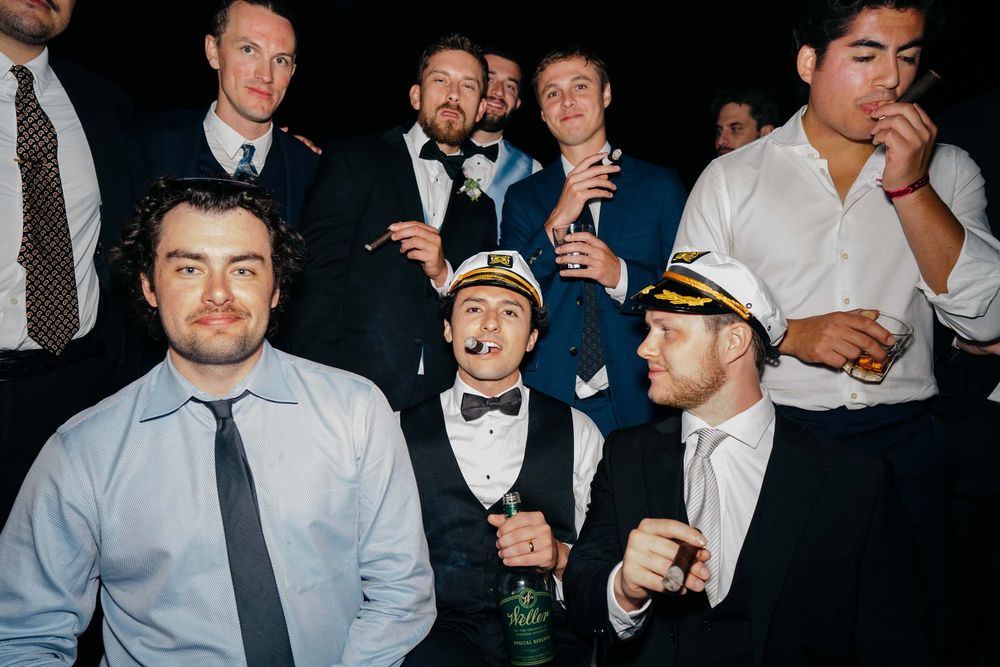 A group of party guests in formal attire enjoying drinks and conversation at an evening celebration event.