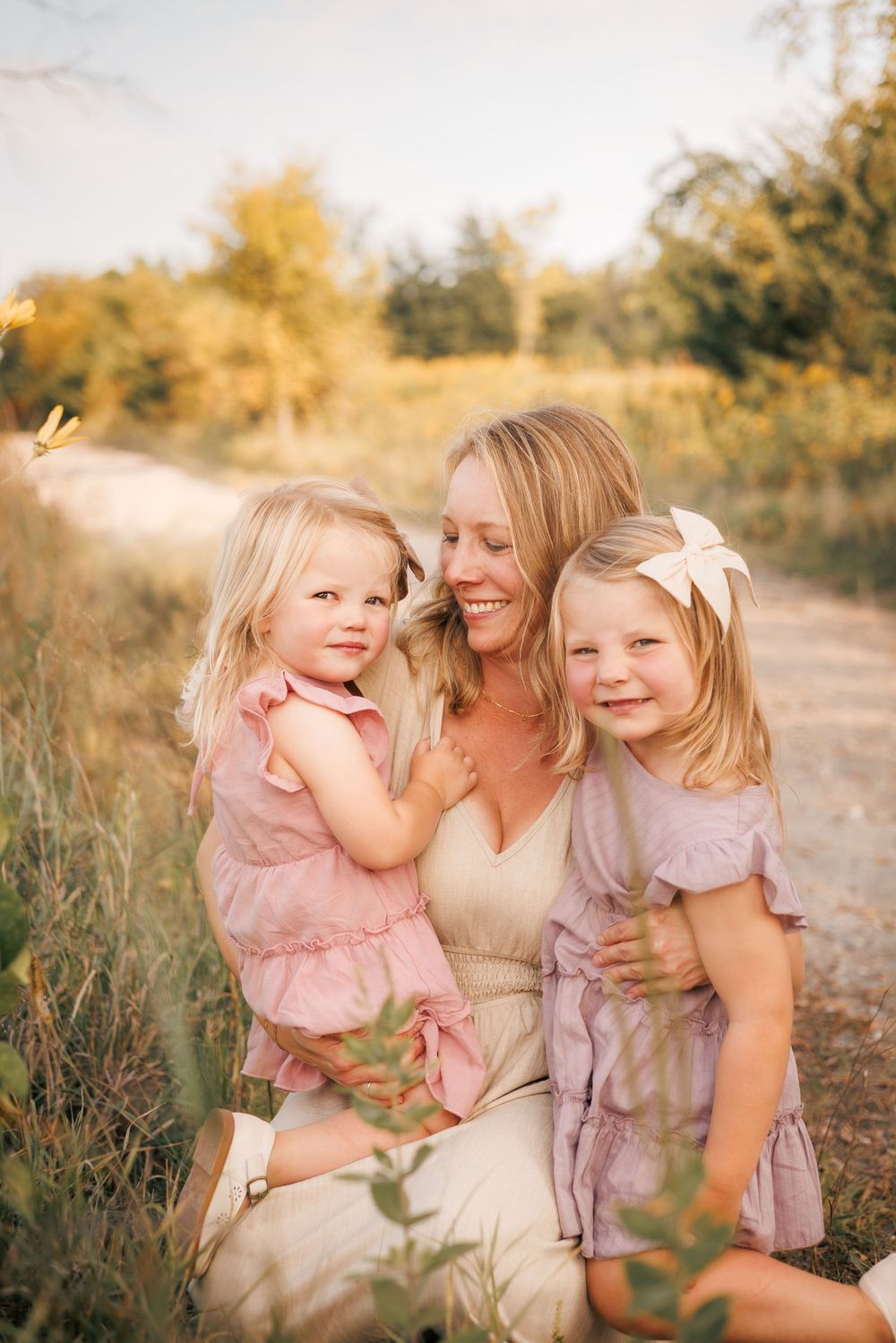 A joyful outdoor family portrait session in warm golden sunlight with soft pink and lavender outfits.
