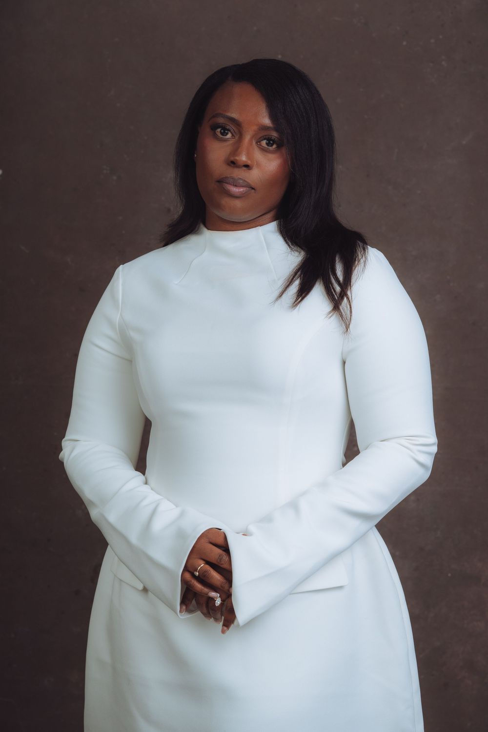 Stylish white turtleneck sweater photographed against moody dark background.