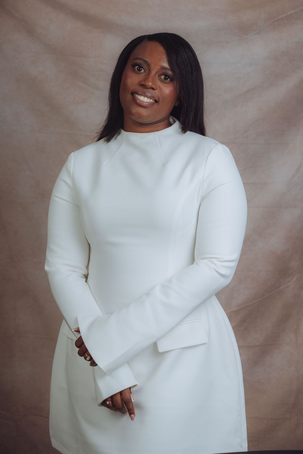 Contemporary fashion portrait in minimalist white sweater against neutral backdrop.