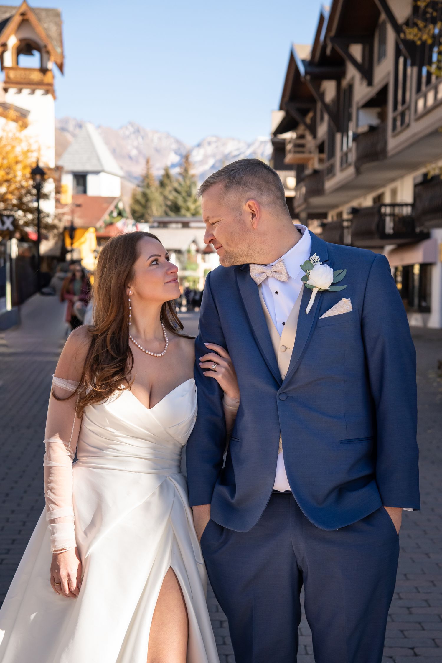 A bride and groom share romantic moments in Vail Village with the mountains and village in the background.
