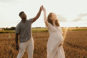 Photographe de couple grossesse yvelines. Couple qui danse dans les champs.