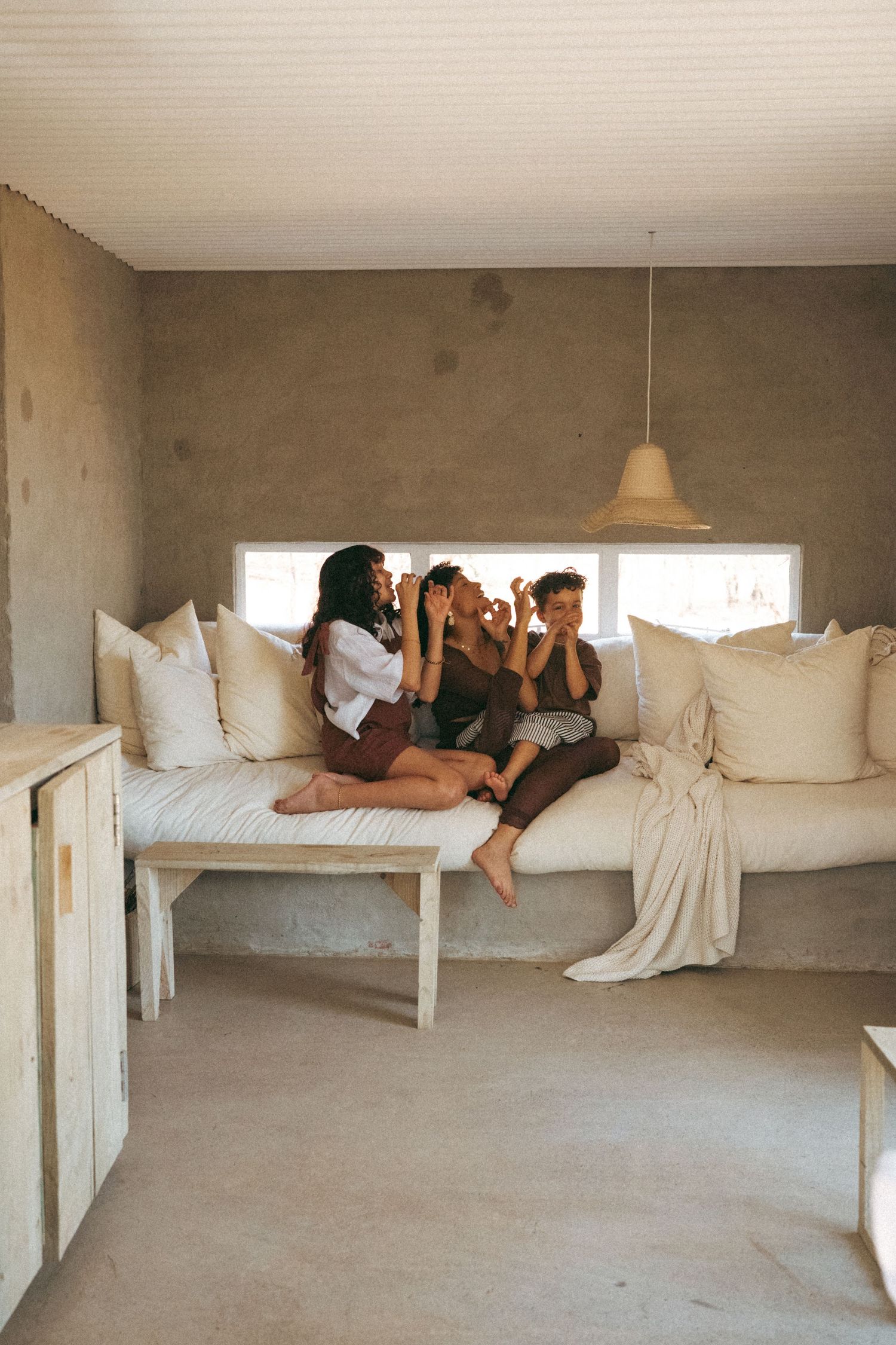 Minimalist white bedroom with people resting on elevated platform bed.