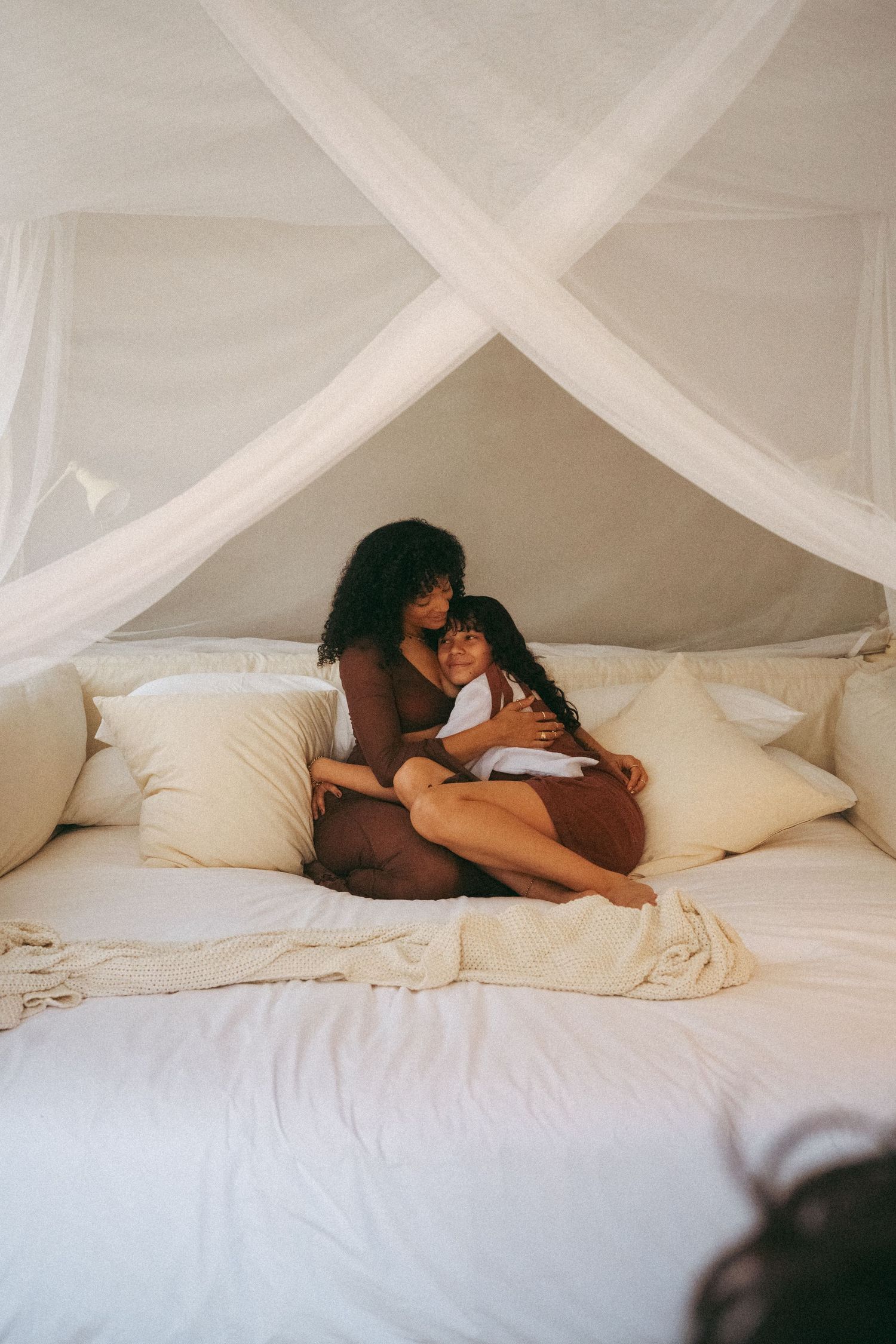 Romantic scene on white bed with flowing canopy drapes.